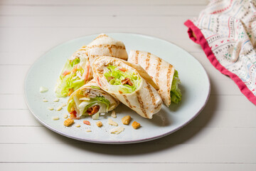 Chicken bacon caeser wrap. Chicken breast fillet wraps on green plate on light wooden background