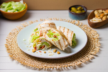 Chicken bacon caeser wrap. Chicken breast fillet wraps on green plate on light wooden background