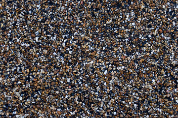 A detailed close-up of colorful gravel pebbles in various shades of brown, black, and white. Perfect for backgrounds, construction materials, landscape design, or environmental themes.