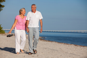 Happy Senior Old Retired Couple Walking Holding Hands Laughing on an Empty Beach