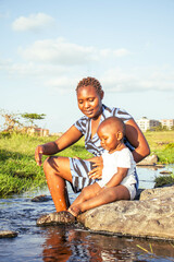 A beautiful young African woman playing outdoors with her baby boy at sunset