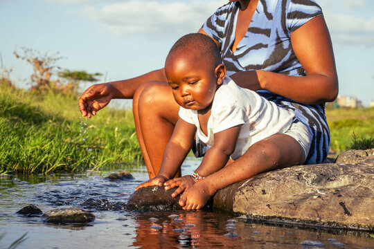 A beautiful young African woman playing outdoors with her baby boy at sunset