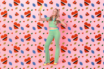 Full body photo of pretty young girl hold device take selfie thumb up wear trendy green print outfit isolated on pink color background