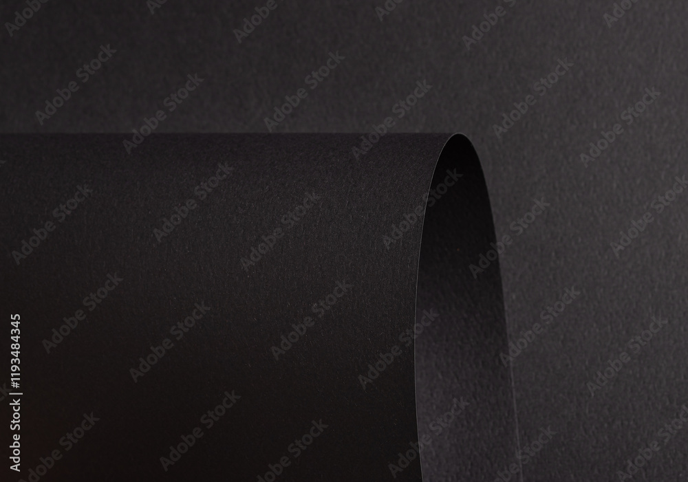 Poster charcoal black paper background with curved, matte surfaces and a smooth, grainy texture. bold dark 