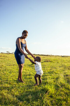 A beautiful young African woman playing with her baby boy outdoors at sunset
