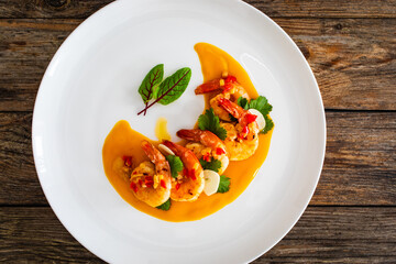 Appetizer of fried shrimps in mango sauce with garlic and chili pepper on wooden table