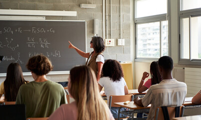 Teacher Explaining Chemistry Formulas to Students in a Classroom Setting at university school. Copy...
