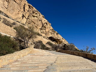 Scenic desert pathway leading up rocky mountain under clear blue sky