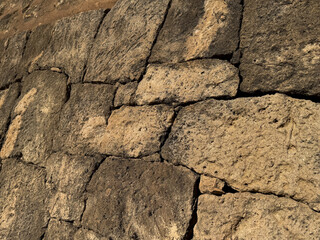 Weathered stone wall texture with sunlit natural patterns