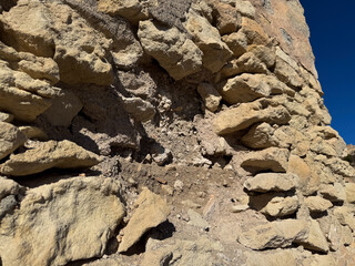 Ancient stone wall with texture and erosion in bright sunlight