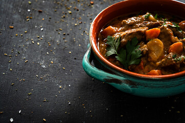 Beef goulash with vegetables on black table