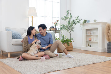 Asian couple spends quality time with their pug dog in their living room
