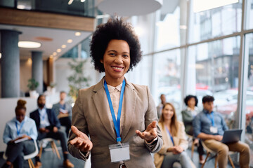 Black female business leader giving speech on seminar and looking at camera.