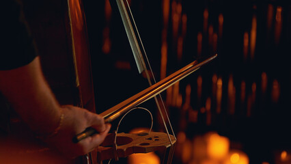Close-up of a double bass being played surrounded by electric candles. A candlelight concert on the Philharmonic stage.