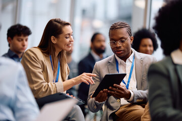 Multiracial colleagues using digital tablet during business seminar in board room.