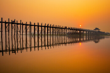 Silhouette of U Bein bridge at sunset in Myanmar.  and reflecting bridge the water