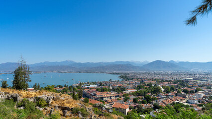 Naklejka premium View of Fethiye city, marina and Mediterranean Sea, Turkey. Walking around resort town at foot of the mountains in southwestern Turkiye