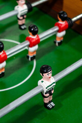 Fototapeta premium Foosball table with players representing Sport Lisboa e Benfica and Sporting Clube de Portugal, highlighting a friendly football rivalry in a playful setting.
