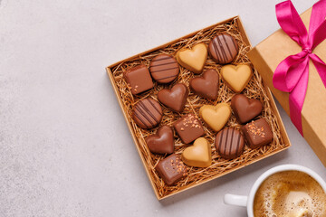 A romantic Valentines Day setup featuring a box of assorted chocolates and a steaming cup of coffee