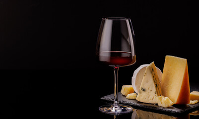 A refined selection of aged cheeses presented on a board, accompanied by a glasses of wine