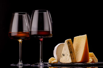 A refined selection of aged cheeses presented on a board, accompanied by a glasses of wine