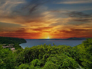 the blue waters of Culebra Bay, lush green trees and powerful clouds at sunset in Liberia Guanacaste Costa Rica