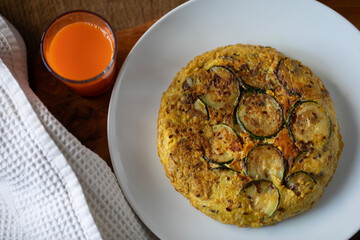 VEGETARIAN FRITTATA ON WHITE PLATE ORGANIC CARROT JUICE WHITE Waffle cloth on wooden surface