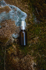 Essential oil bottle placed on moss-covered rock in a natural setting
