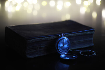 Vintage Pocket Watch on Antique Book with Bokeh Lights Background