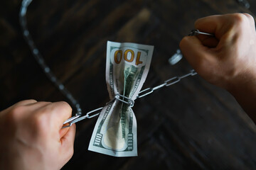 Hands Breaking Chains Wrapped Around Hundred Dollar Bill Symbolizing Financial Freedom