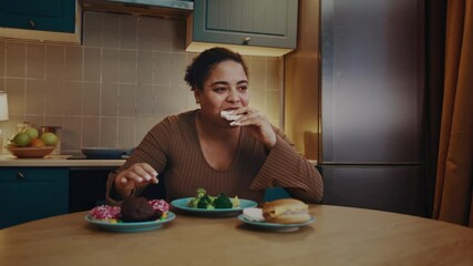 African American woman quickly eats junk food at table
