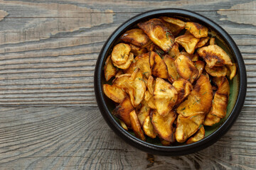 Homemade parsnip chips in a bowl. Rustic wooden background with space for text.