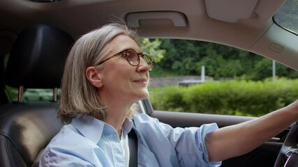 Satisfied happy Caucasian woman retiree female senior tourist pensioner car driver riding in automobile driving steer vehicle auto driveway opened window wind fresh air wellbeing travelling retirement