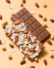 Milk chocolate bars with hazelnut, almond, coconut on beige background. Confectionery. Demonstration of sides of craft chocolate bars with nuts. Sweet food concept. Top view.