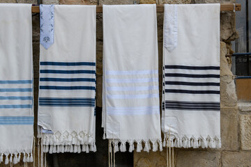 Tallit or tallis (plural tallisim), Jewish prayer shawls, neatly hanging on a display rack outside a Judaica store in Jerusalem, Israel.