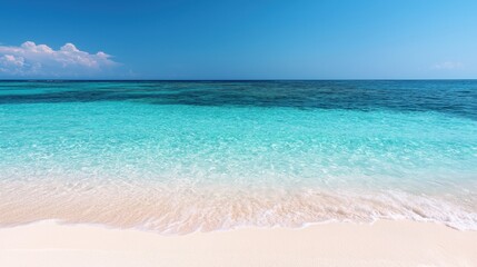 Fototapeta premium A serene beach scene featuring crystal-clear turquoise waters meeting a soft sandy shore under a bright blue sky.