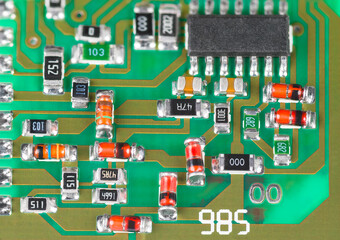 Closeup a surface mount assembly of electronic components on printed circuit board. Red or orange...