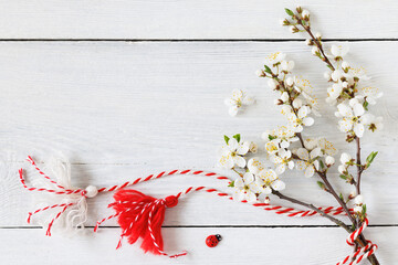 Blooming branches of cherry plum on a wooden background, red and white decor symbol of Martenitsa spring holiday March 1. Martisor, Baba Marta, greeting card.