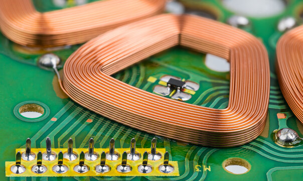 Stator part of brushless DC electric motor embedded on printed circuit board. Closeup of coil copper wire winding with Hall effect sensor on green PCB detail inside engine with electronic commutation.