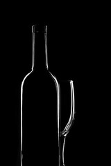 Bottle and glass on a dark background, light contours