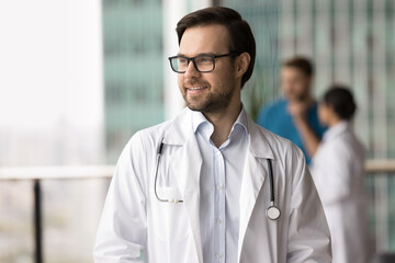Young Caucasian male doctor, therapist, cardiologist wearing eyeglasses and white lab coat,...