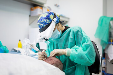An unrecognizable surgeon performs hair extraction on a patient during a hair surgery operation.Concept of hair operation or adding hair through surgery. ©  Yistocking