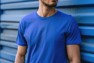 A man wearing a plain blue t shirt against a blue wall.