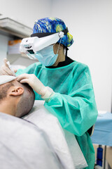 Vertical photo of an unrecognizable surgeon performing hair extraction on a patient during a hair surgery operation.Concept of hair operation or adding hair through surgery. ©  Yistocking