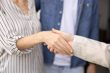Couple of customers shaking hands with real estate insurance agent, mortgage broker, realtor, closing agreement, getting rental, buying house. Close up of handshake
