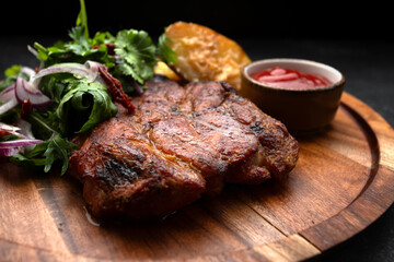 Grilled meat steak with spicy sauce, baked potato and herbs with onions