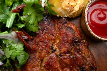 Grilled meat steak with spicy sauce, baked potato and herbs with onions