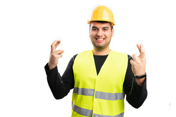 Cheerful builder man making good luck gesture fingers crossed