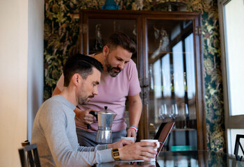 two lgtbi couple boys drink coffee at home while looking at the computer