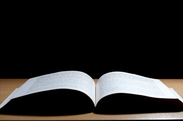 Open Book on Wooden Table with Black Background